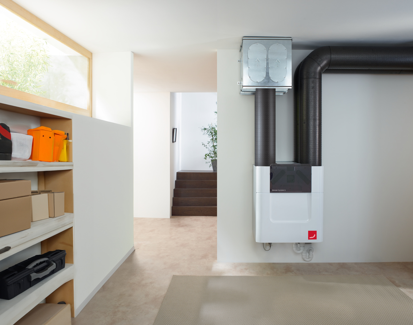 Frische Luft im ganzen Haus Kompaktes Zehnder-Lüftungsgerät mit angeschlossenen Luftkanälen, installiert im Flur eines Wohnhauses