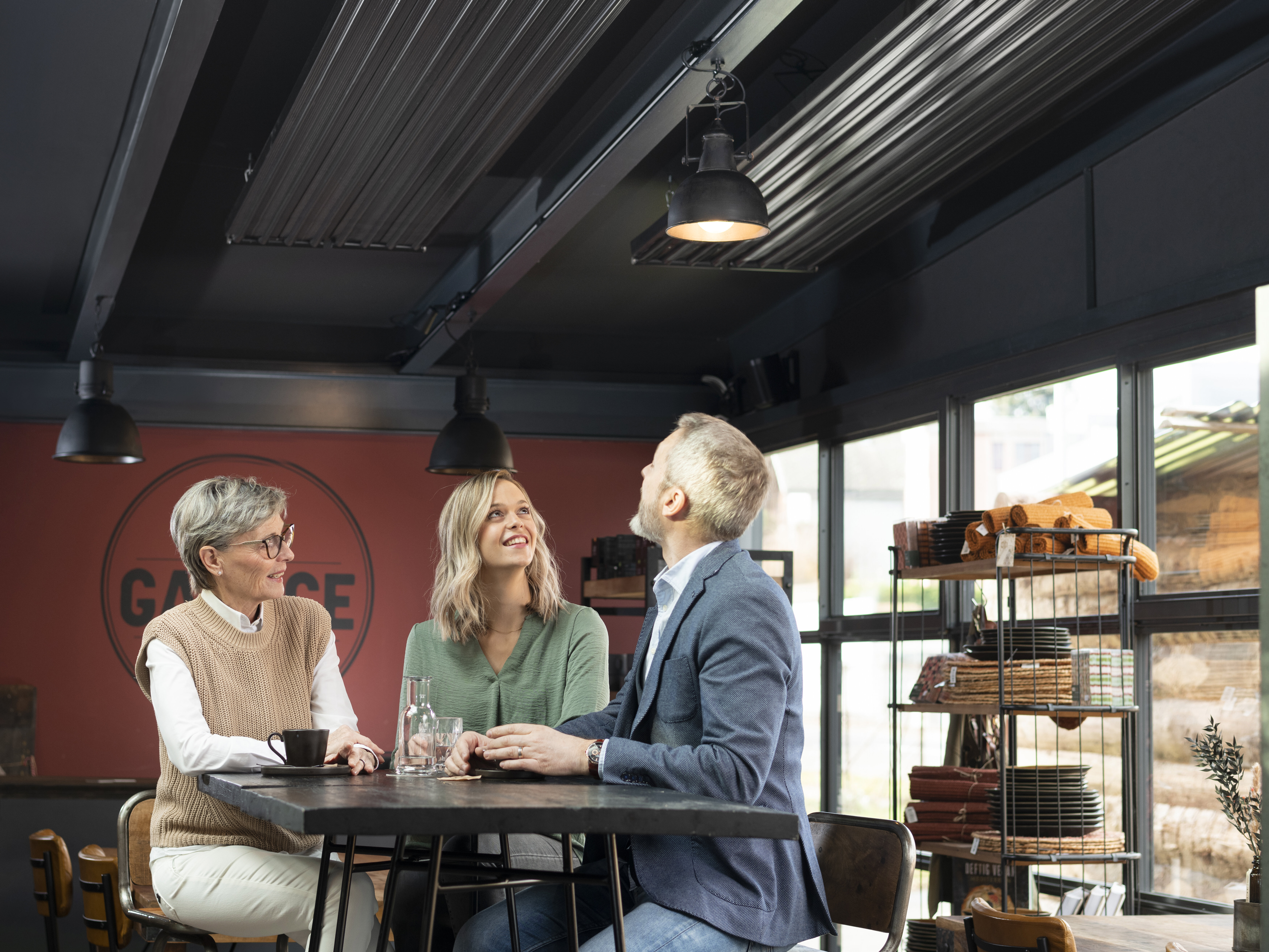Personen in einem Café freuen sich über Deckenstrahlplatten